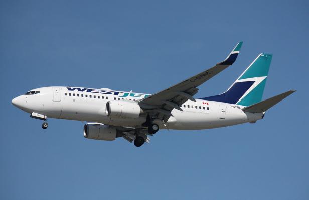 Ein Flugzeug der Fluggesellschaft WestJet im Landeanflug vor blauem Himmel.