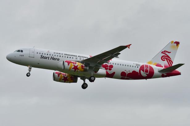 Ein Flugzeug der Shenzhen Airlines mit bunten Blumenmustern im Landeanflug.