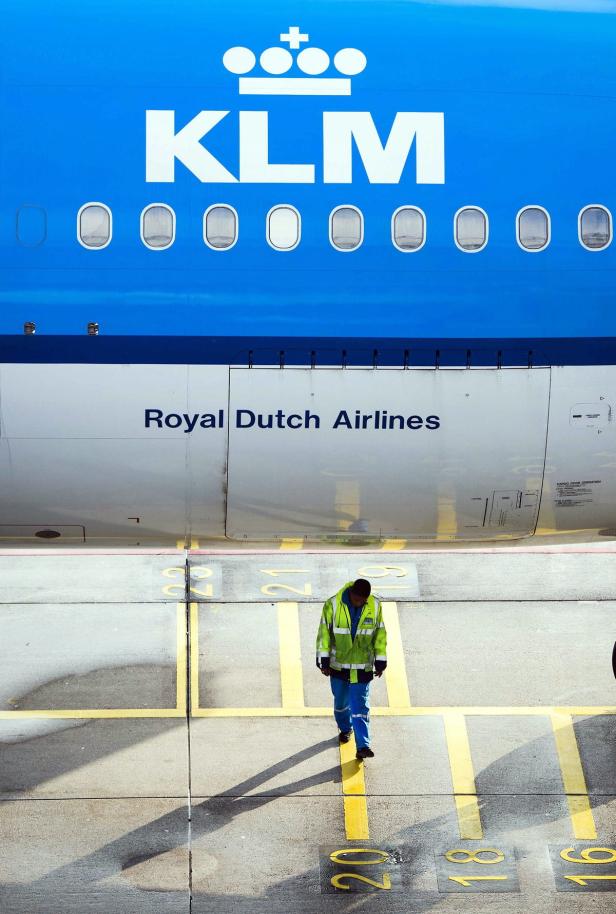 Ein Arbeiter in Warnweste geht an einem Flugzeug der KLM entlang.