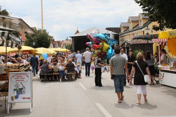 Ein belebtes Straßenfest mit Menschen, Ständen und einem Ballonverkäufer.
