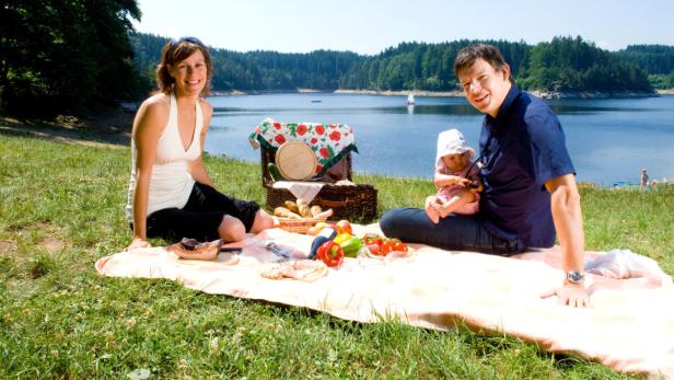 Eine Familie macht ein Picknick am Ufer eines Sees.