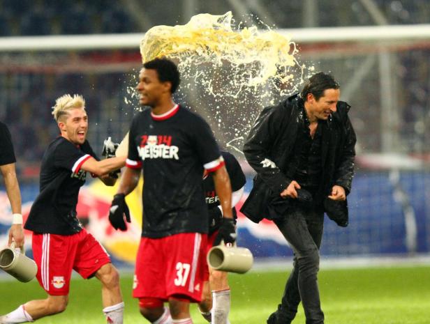 Fußballspieler schütten Bier über einen Trainer.