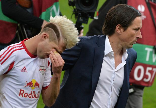 Ein enttäuschter Fußballspieler mit ausgefallener Frisur und sein Trainer stehen auf dem Spielfeld.