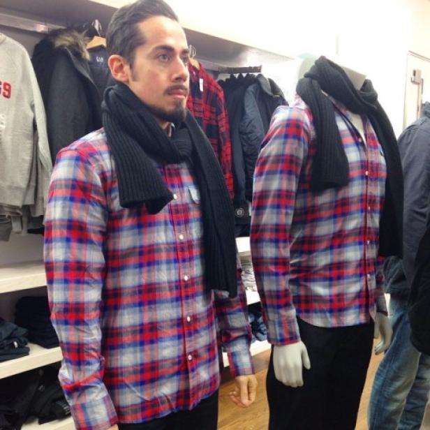 Ein Mann und eine Schaufensterpuppe tragen das gleiche karierte Hemd und einen schwarzen Schal.