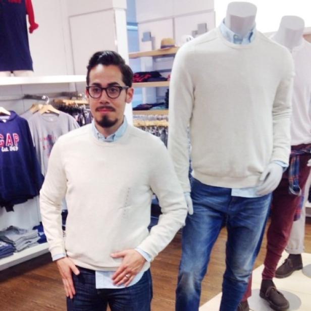 Ein Mann posiert in einem Bekleidungsgeschäft neben einer Schaufensterpuppe mit ähnlicher Kleidung.