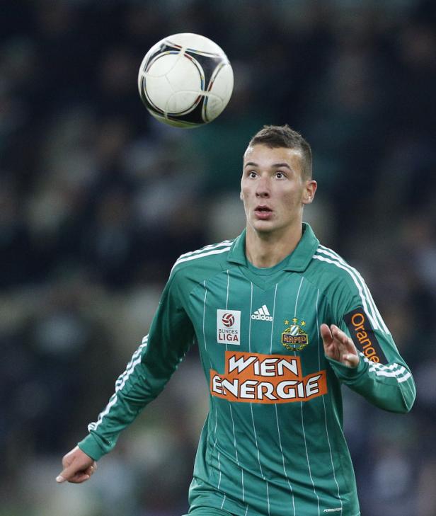Ein Fußballspieler in einem grünen Trikot mit einem Fußball in der Luft.
