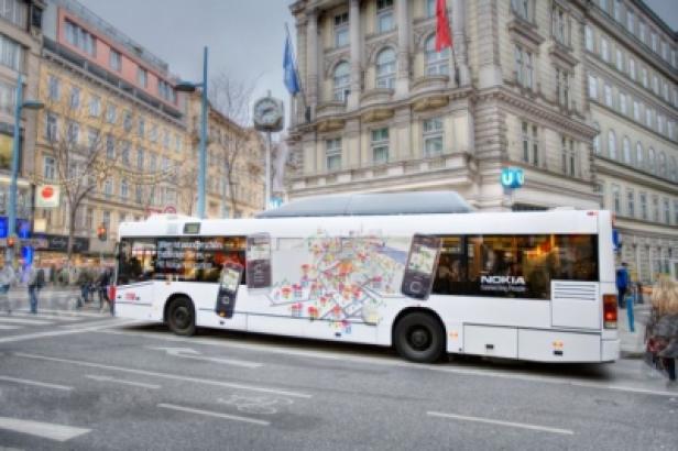 Ein weißer Bus mit Nokia-Werbung fährt durch eine Stadt.
