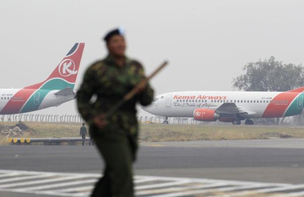 Ein Soldat steht vor zwei Flugzeugen der Kenya Airways auf einem Flugfeld.