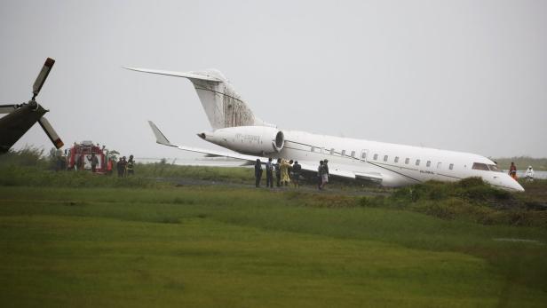 Ein weißes Flugzeug ist neben einer Feuerwehr auf einer Grasfläche verunglückt.