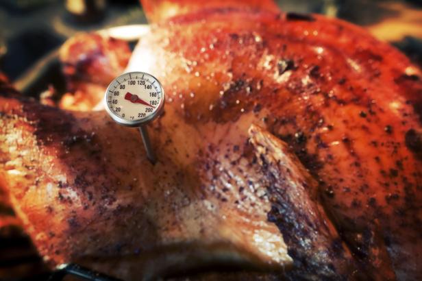 Ein gebratener Truthahn mit einem Thermometer, das die Temperatur misst.