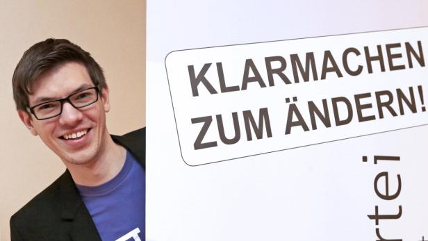 Ein lächelnder Mann mit Brille neben einem Schild mit der Aufschrift „Klarmachen zum Ändern!“.