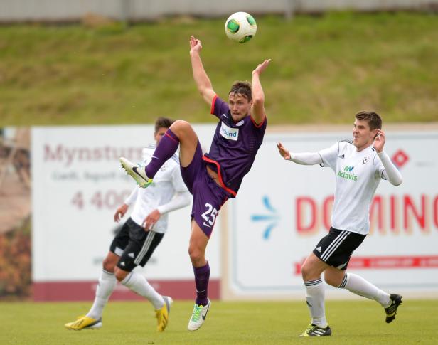 Ein Fußballspieler springt, um den Ball mit dem Fuß zu spielen, während andere Spieler zusehen.