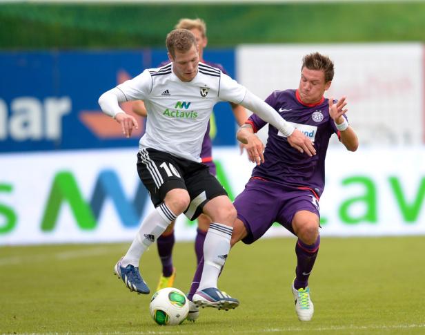 Zwei Fußballspieler kämpfen um den Ball auf dem Spielfeld.