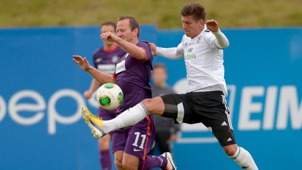 Zwei Fußballspieler kämpfen um den Ball während eines Spiels.