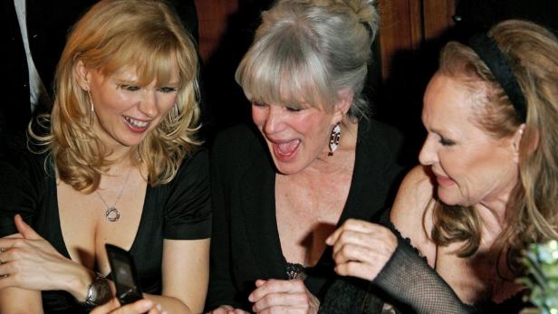 Drei Frauen mittleren Alters schauen amüsiert auf ein Mobiltelefon.