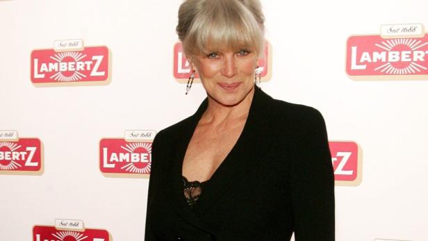 Eine Frau posiert vor einer Wand mit Lambertz-Logos.