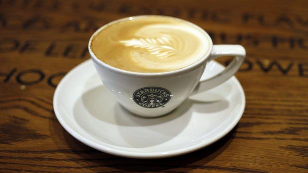 Eine Tasse Starbucks-Latte mit Latte Art auf einem Holztisch.