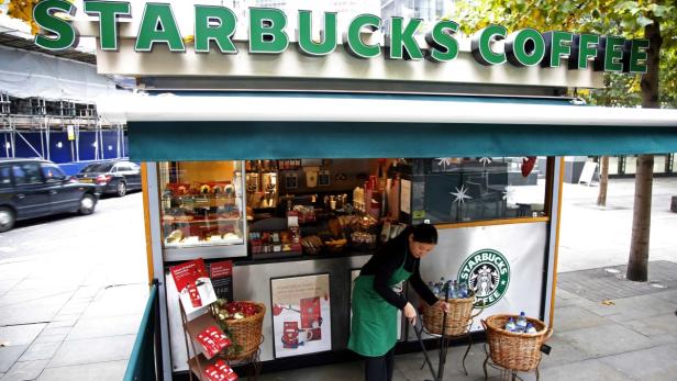 Eine Starbucks-Filiale im Freien mit einer Mitarbeiterin, die Wasserflaschen in Körbe sortiert.