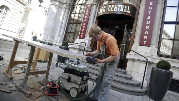 Ein Handwerker bearbeitet eine Holzplatte vor dem Café Central in Wien.