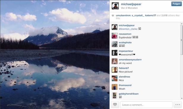 Ein Bergsee spiegelt einen schneebedeckten Berg und den bewölkten Himmel wider.