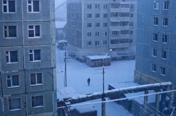 Eine verschneite Stadtlandschaft mit einem Mann, der durch den Schnee geht.