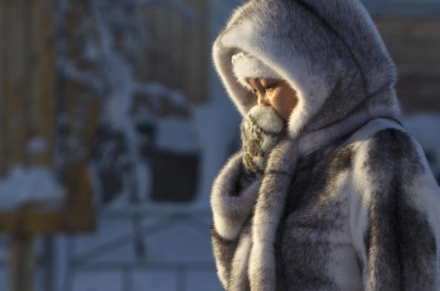 Eine Frau mit Pelzkapuze und Handschuhen im Schnee.