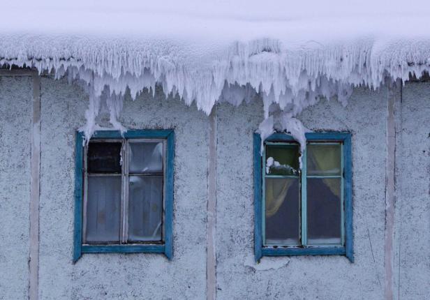 Ein Haus mit vereisten Fenstern und einem Dach voller Eiszapfen.