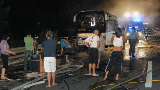 Die Insassen des Busses kamen mit dem Schrecken davon Nach einem Busunfall stehen Menschen barfuß auf der Straße, während die Feuerwehr eintrifft.