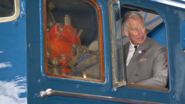 König Charles III. in der Fahrerkabine einer blauen Lokomotive.
