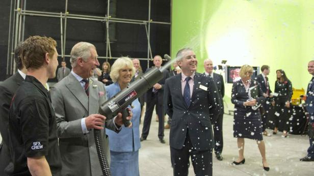 König Charles und Camilla testen eine Schneekanone auf jemanden.