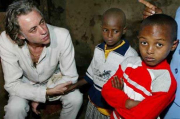 Ein Mann sitzt neben zwei afrikanischen Kindern.