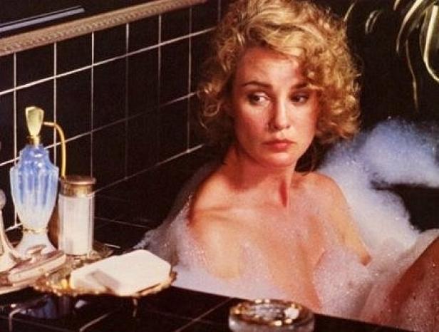 Eine Frau mit blonden Locken entspannt in einer mit Schaum gefüllten Badewanne.