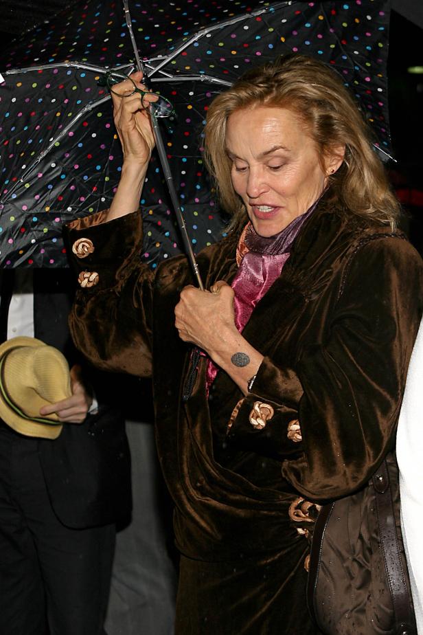 Jessica Lange unter einem bunten Regenschirm bei Regen.