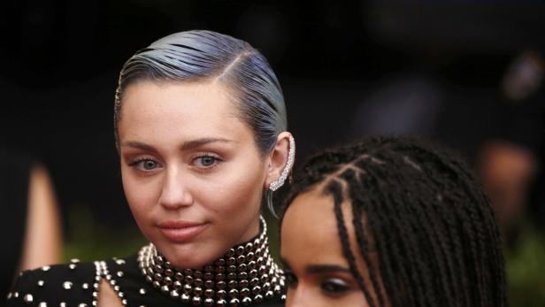 Miley Cyrus mit blau gefärbten Haaren und einem auffälligen Ohrring.