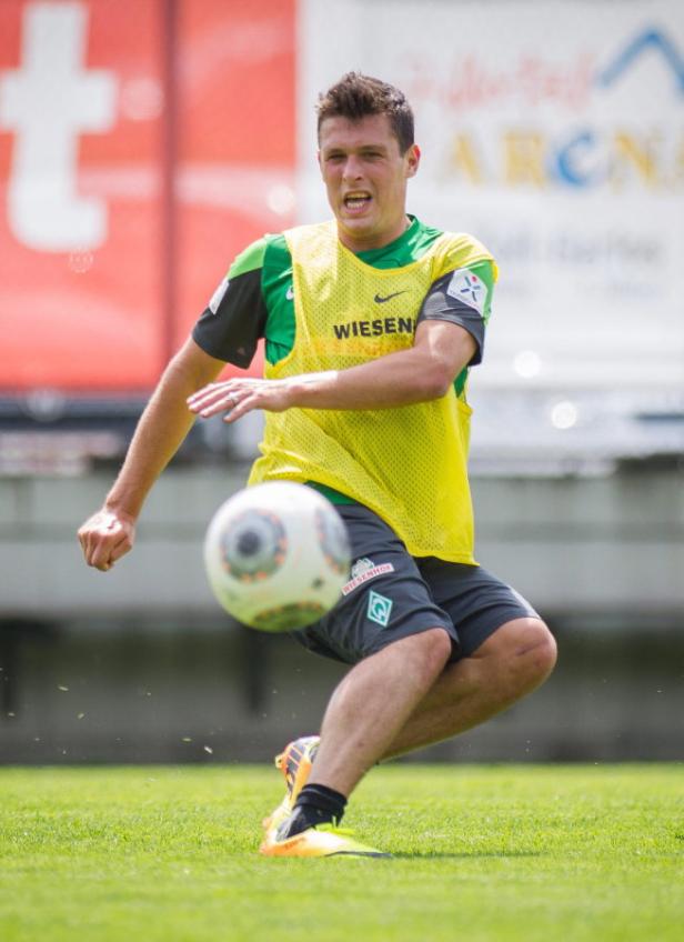 Ein Fußballspieler in Sportkleidung schießt einen Fußball.