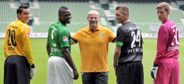 Fünf Fußballspieler von Werder Bremen posieren für ein Foto auf dem Rasen.