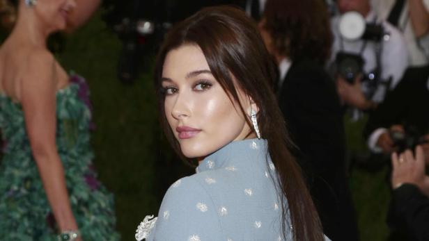 Hailey Bieber blickt über ihre Schulter auf dem roten Teppich.