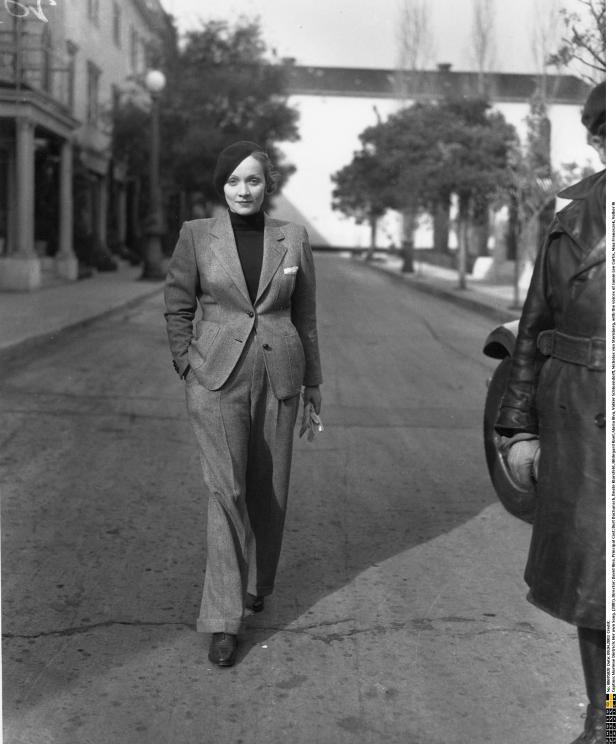 Marlene Dietrich in einem Hosenanzug auf einer Straße.