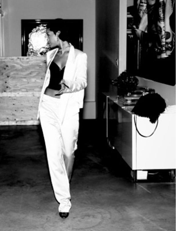 Eine Frau in einem weißen Hosenanzug posiert in einem Innenraum.