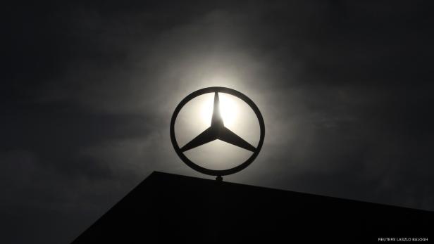 Das Mercedes-Benz-Logo vor einem dunklen, bewölkten Himmel.