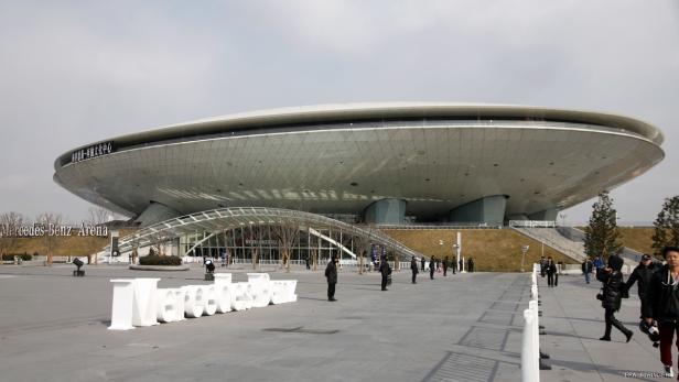Die Mercedes-Benz Arena in Shanghai mit Menschen im Vordergrund.