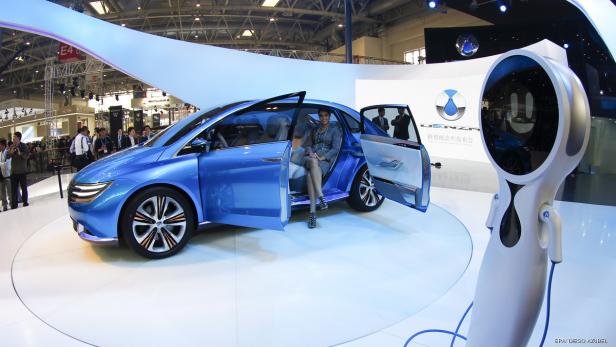 Eine Frau sitzt in einem blauen Denza-Konzeptfahrzeug auf einer Automobilausstellung.
