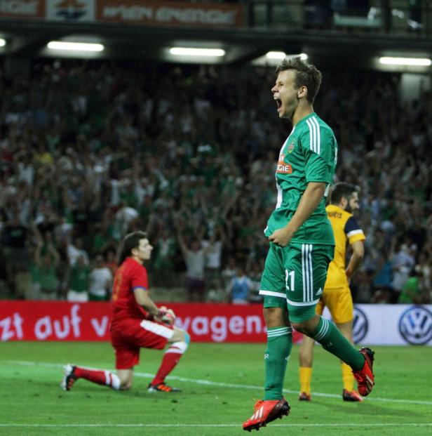 Ein Fußballspieler in Grün jubelt vor einer Zuschauermenge.