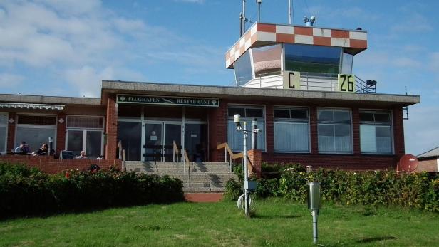 Das Gebäude des Flughafens mit Restaurant und Kontrollturm unter blauem Himmel.