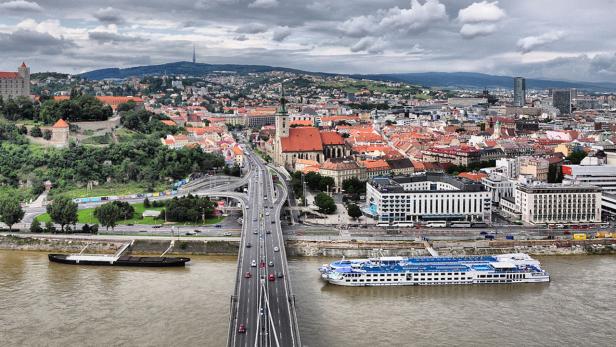 Blick auf Bratislava mit der Burg, der Donau und einer Brücke.