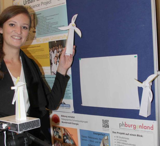 Eine junge Frau präsentiert ein Schulprojekt zum Thema Windenergie mit selbstgebastelten Windrädern.