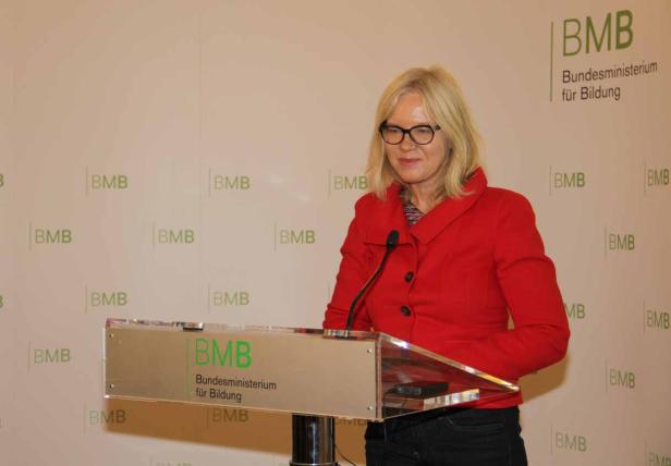 Eine Frau in roter Jacke steht an einem Rednerpult des Bundesministeriums für Bildung.