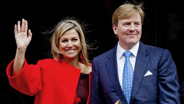 König Willem-Alexander und Königin Máxima der Niederlande lächeln und winken.
