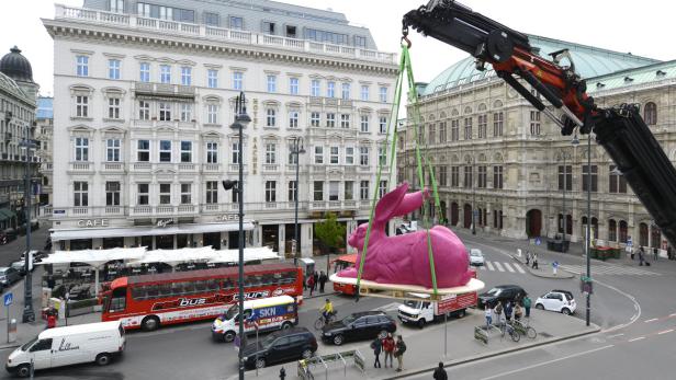 Ein riesiger, pinkfarbener Hase wird mit einem Kran in Wien transportiert.