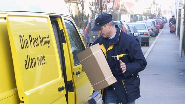 Ein Postbote entlädt ein Paket aus einem gelben Lieferwagen.